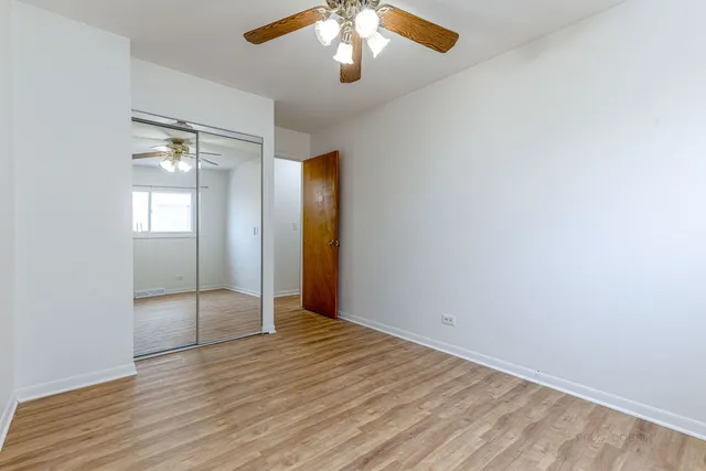 an empty room with wooden floor mirror and windows