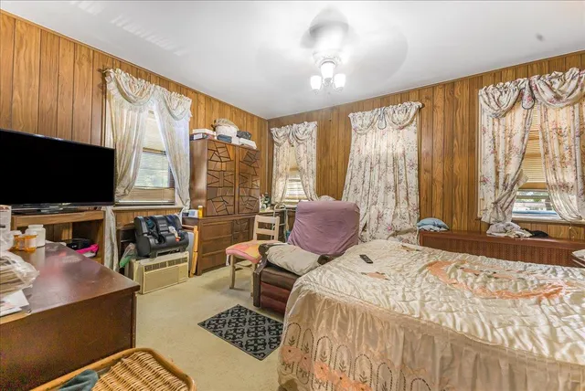 a bedroom with a bed and a flat tv screen next to a large window