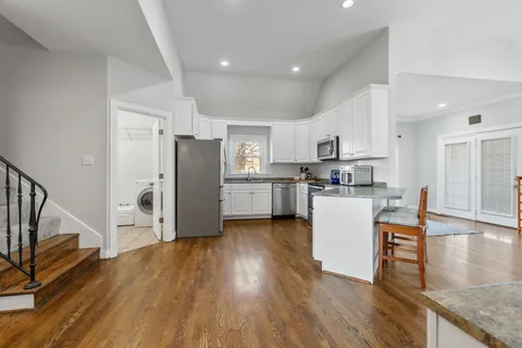 a kitchen with stainless steel appliances granite countertop a refrigerator a stove top oven and a wooden floor