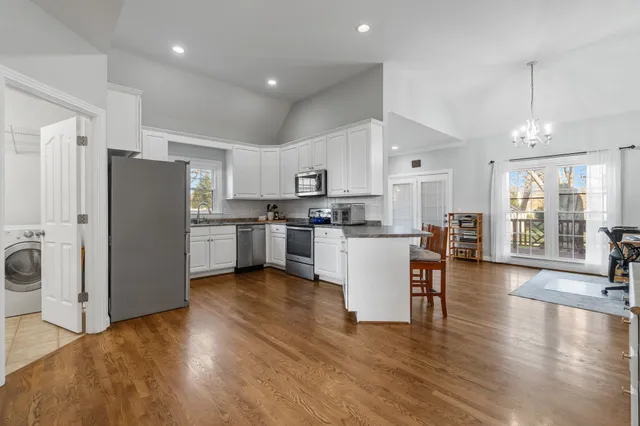 a kitchen with a refrigerator a stove top oven a dining table and chairs with wooden floor