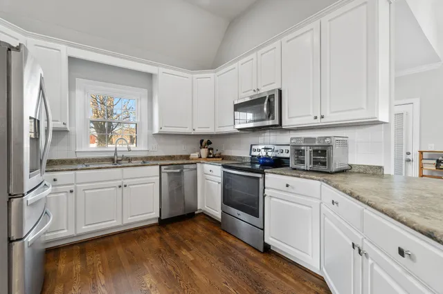 a kitchen with stainless steel appliances granite countertop a stove a sink and white cabinets