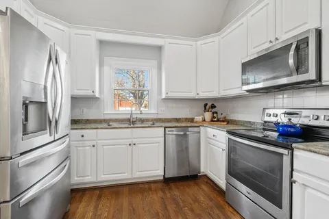 a kitchen with stainless steel appliances granite countertop a stove a sink and a microwave