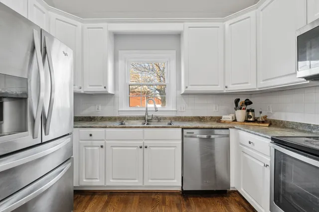 a kitchen with stainless steel appliances granite countertop a sink a stove a refrigerator and cabinets