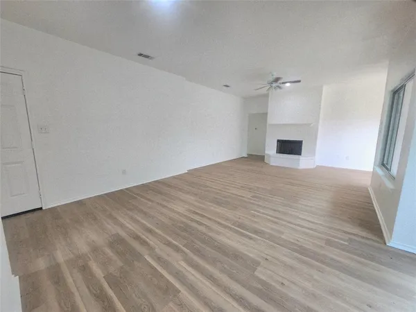 a view of empty room with wooden floor and fireplace