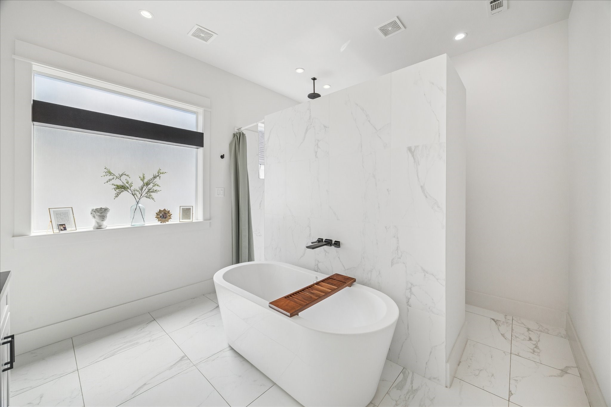 1311 Laird Street Houston, TX 77008 - Photo 25 of 28 The primary bathroom wows with a walk-in rain shower with built-in seating, a freestanding soaking tub and swaths of stone finishes.