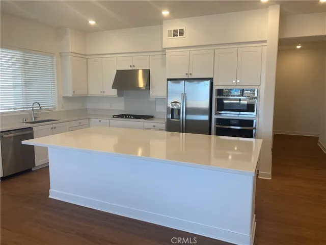 a large kitchen with stainless steel appliances a refrigerator and a sink