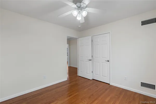 a view of an empty room and chandelier fan