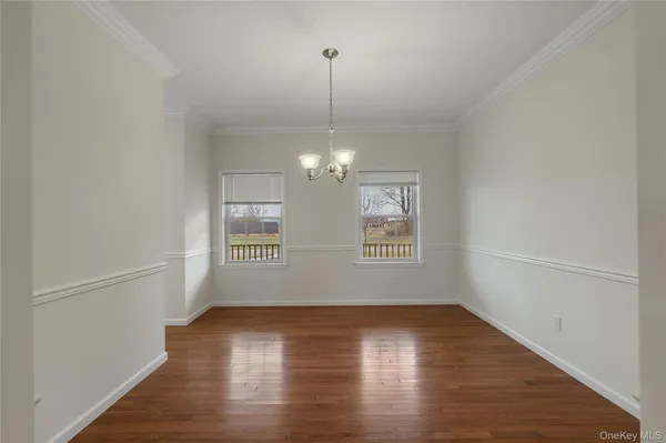 an empty room with wooden floor chandelier and windows