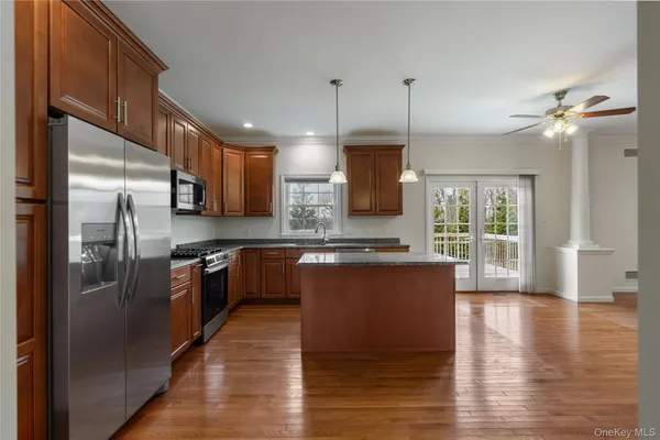 a large kitchen with stainless steel appliances granite countertop a refrigerator a oven a large island with wooden cabinets and floors