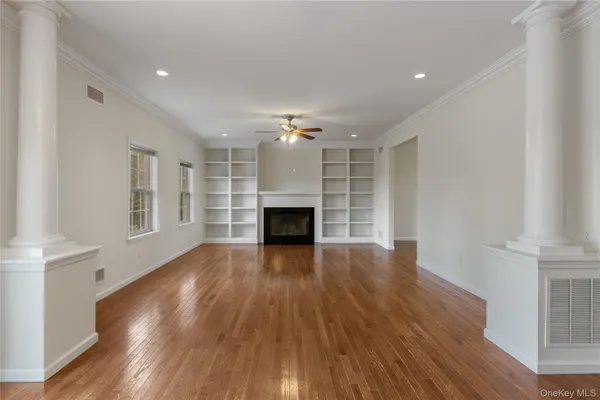 a view of an empty room with wooden floor fireplace and a window