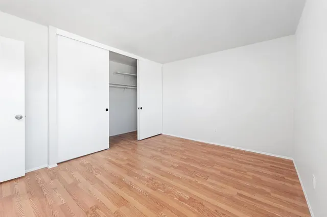 a view of empty room with wooden floor and window