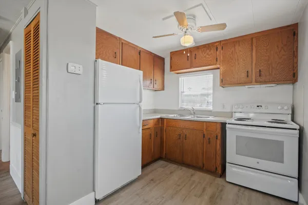 a kitchen with stainless steel appliances granite countertop a refrigerator a sink dishwasher a stove and white countertops with wooden floor