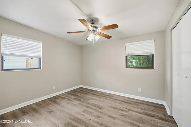 an empty room with a window and a ceiling fan