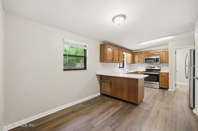 a kitchen with stainless steel appliances granite countertop a stove a sink dishwasher and a refrigerator with wooden floor