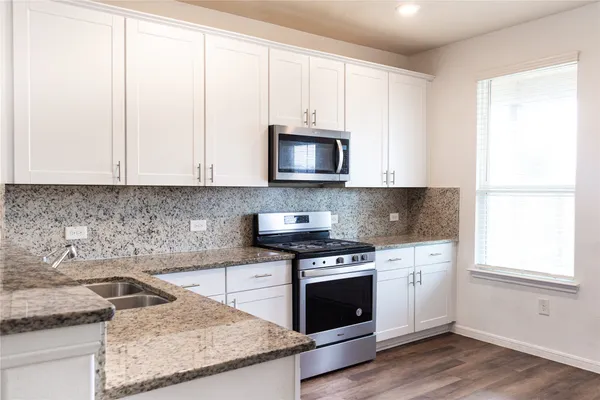 a kitchen with granite countertop white cabinets and white stainless steel appliances