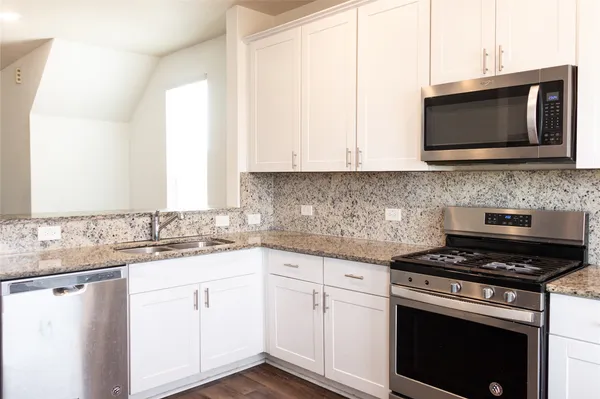 a kitchen with stainless steel appliances granite countertop a sink stove and microwave