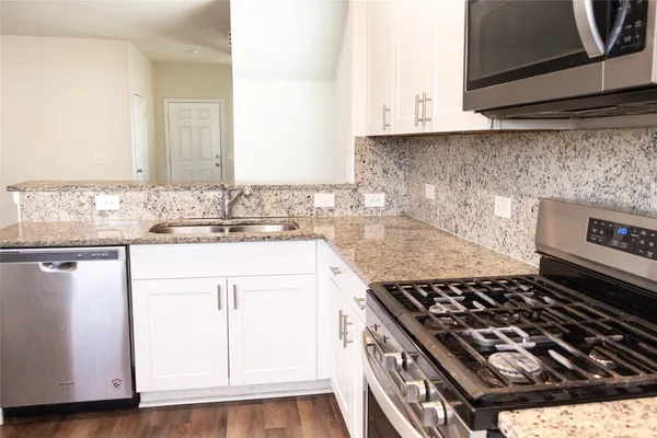 a kitchen with granite countertop a sink stove and cabinets