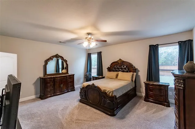 a spacious bedroom with a bed a dresser and mirror