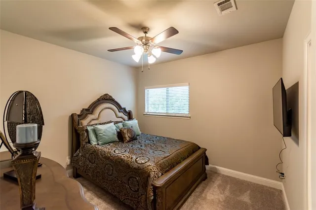 a bedroom with a bed and a flat tv screen on the dresser