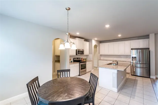 a kitchen with stainless steel appliances granite countertop a sink a stove a refrigerator a dining table and chairs