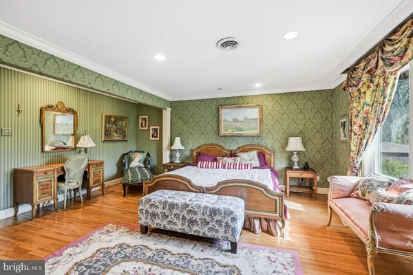 a bedroom with a bed a chair and next to a window
