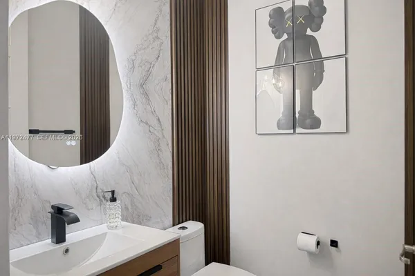 a bathroom with a sink and mirror with toilet