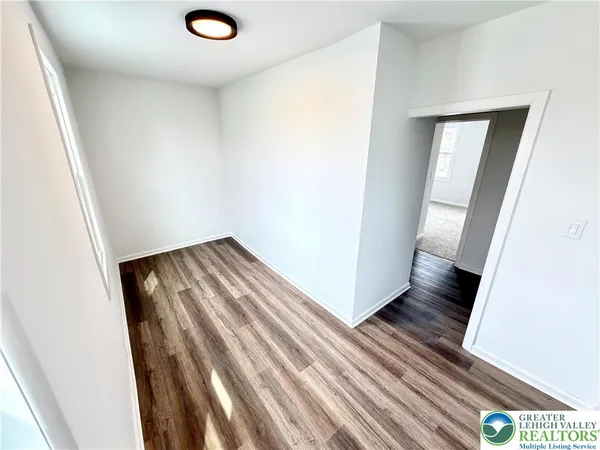an empty room with wooden floor and entrance