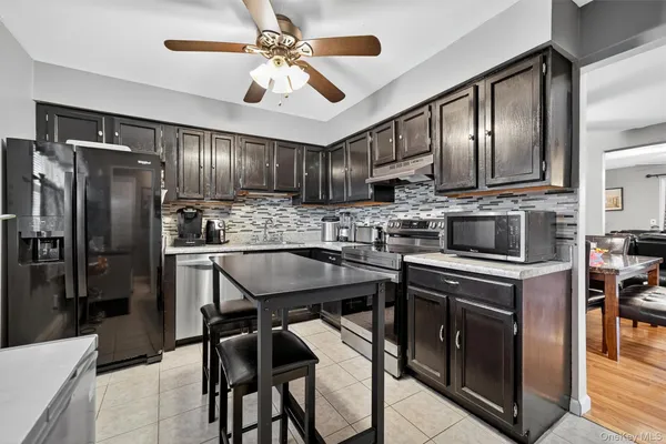 a kitchen with stainless steel appliances granite countertop a stove top oven a refrigerator a sink and chairs