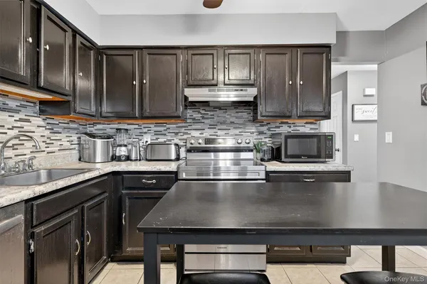 a kitchen with kitchen island granite countertop a sink a stove and cabinets