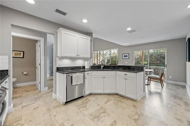 a kitchen with granite countertop white cabinets and stainless steel appliances