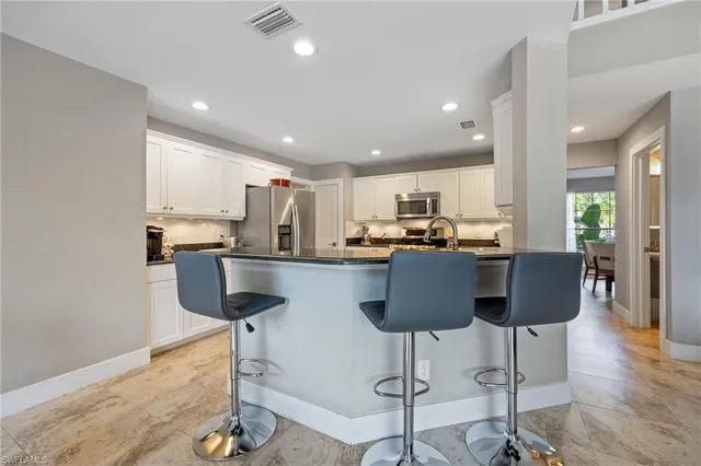 a kitchen with stainless steel appliances granite countertop a refrigerator a stove a sink and a dining table with wooden floor