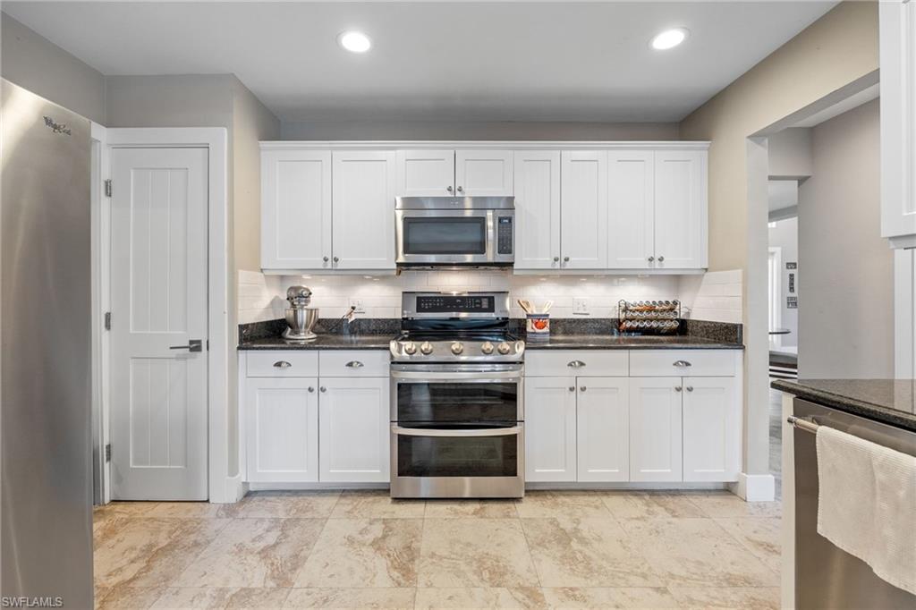 5188 Mabry Drive Naples, FL 34112 - Photo 16 of 49 a kitchen with granite countertop white cabinets and stainless steel appliances