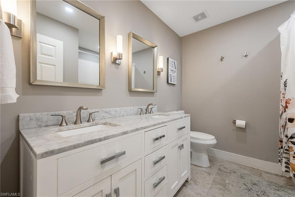 5188 Mabry Drive Naples, FL 34112 - Photo 27 of 49 a bathroom with a granite countertop toilet sink and mirror