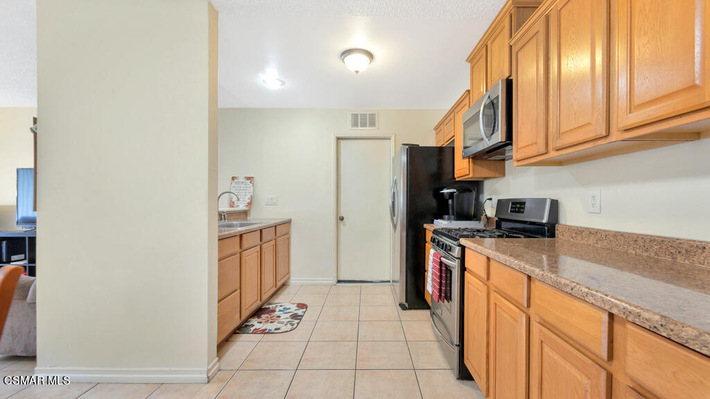 152 Ripley Street Camarillo, CA 93010 - Photo 12 of 36 a kitchen with stainless steel appliances granite countertop a refrigerator a stove and a sink with large cabinets