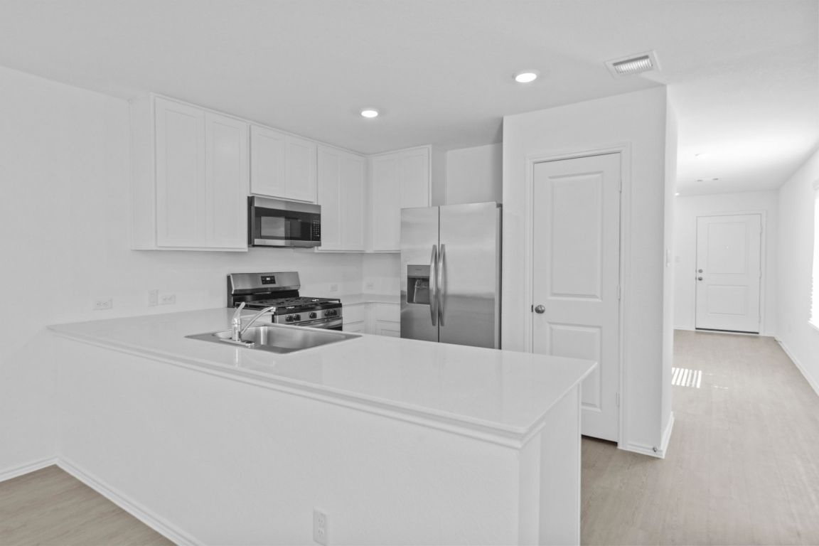 245 Ammolite Lane Maxwell, TX 78656 - Photo 8 of 17 a kitchen with a refrigerator and a stove top oven