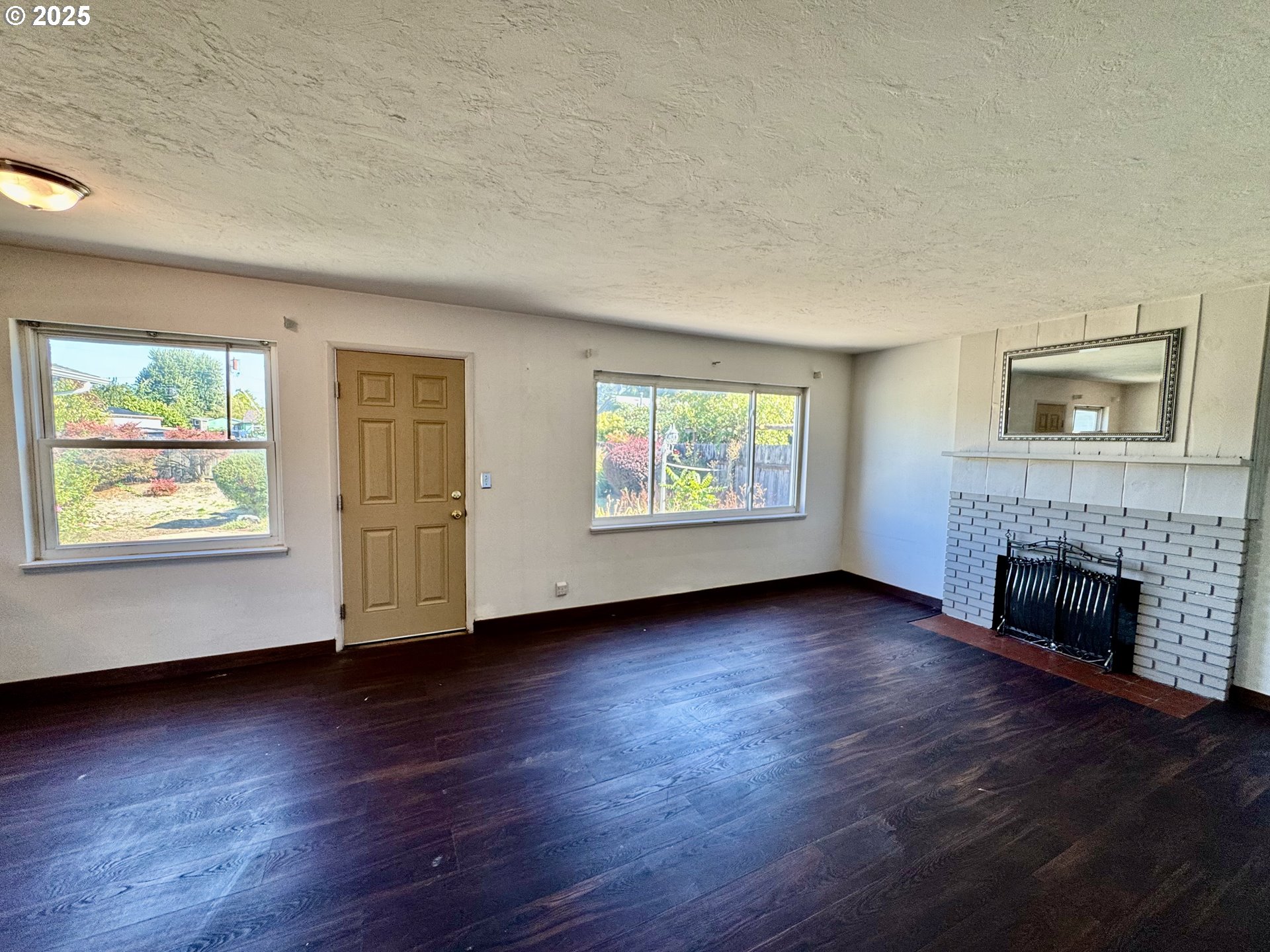 1915 Carter Lane Springfield, OR 97477 - Photo 13 of 30 an empty room with windows fireplace and wooden floor