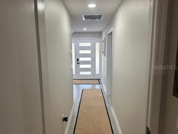 a view of a hallway with wooden floor and a bathroom