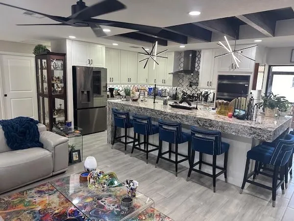 a kitchen with stainless steel appliances granite countertop a table chairs sink and cabinets