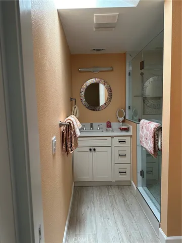a bathroom with a granite countertop sink a mirror and shower