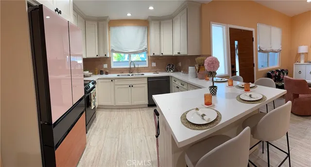 a kitchen with stainless steel appliances granite countertop a sink a stove a refrigerator and island with wooden floor