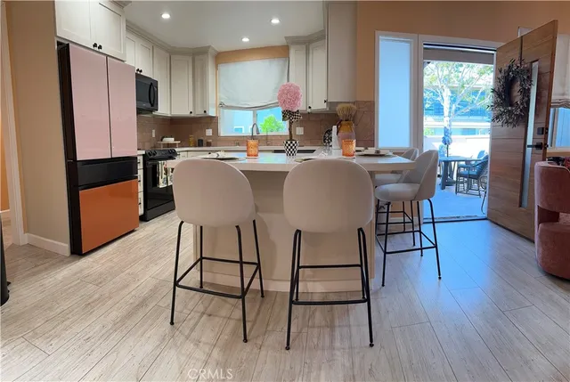 a kitchen with stainless steel appliances granite countertop a dining table chairs refrigerator and sink