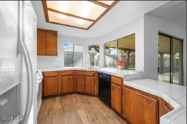 a large kitchen with stainless steel appliances granite countertop a sink and wooden cabinets
