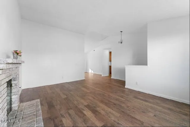 a view of empty room with wooden floor and fireplace