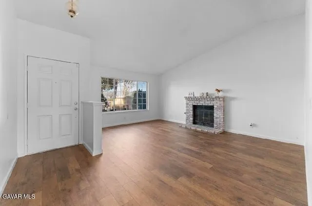a view of empty room with wooden floor and fireplace