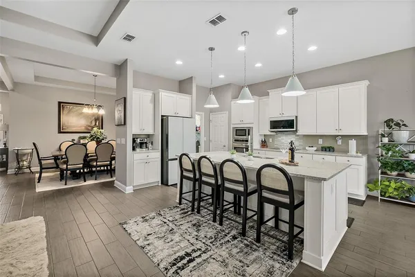 a kitchen with stainless steel appliances kitchen island granite countertop a table and chairs in it