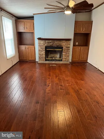 an empty room with wooden floor fireplace and windows