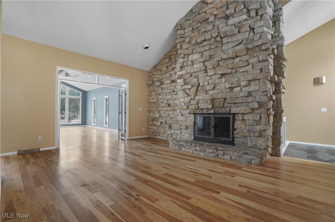 1094 San Raphael Drive Akron, OH 44333 - Photo 12 of 50 Unfurnished living room with high vaulted ceiling, a fireplace, and wood finished floors