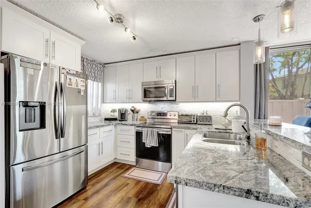 a kitchen with stainless steel appliances a refrigerator and wooden floor