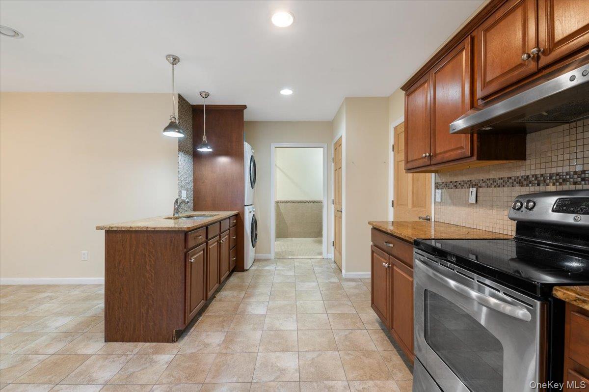 33 Fleets Cove Road Huntington, NY 11743 - Photo 28 of 42 Kitchen featuring stainless steel electric range, light stone counters, estacked washer and dryer, pendant lighting, and recessed lighting