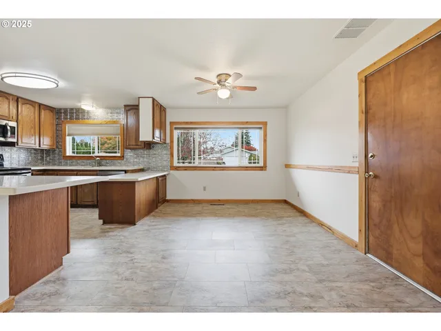 a view of a kitchen with a sink a kitchen island a stove a refrigerator cabinets and a window